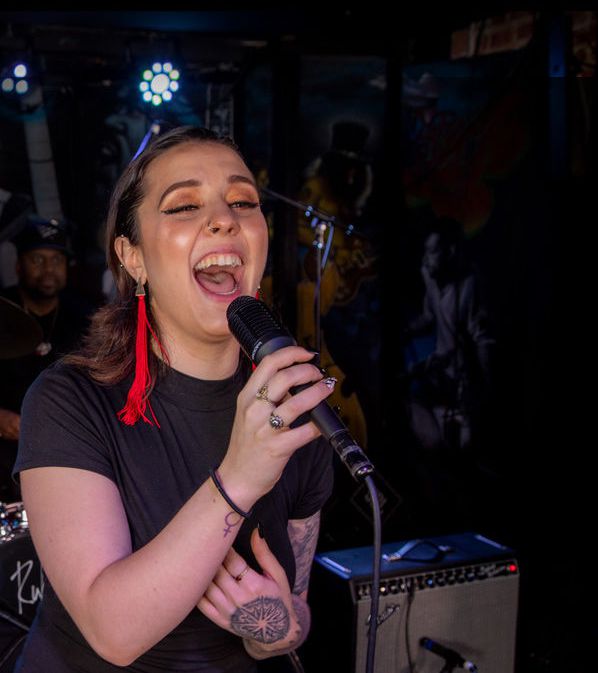 Person singing into microphone with band in background