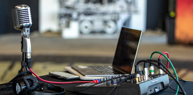 Setup of a podcast set with a microphone, computer, and the Zoom L-8