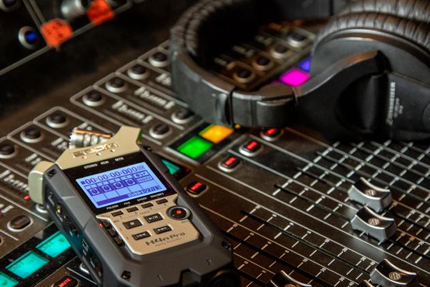 ZOOM H4N PRO resting on top of a studio soundboard, next to a pair of headphones.