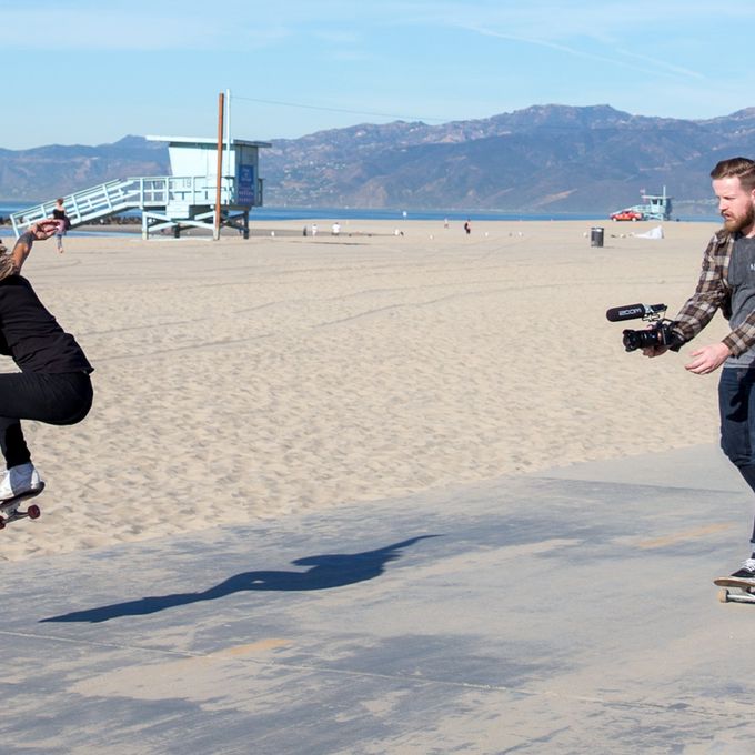 Videographer with F1-SP mounted to a DSLR on a skateboard, filming another skateboarder performing a trick