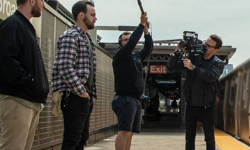 people filming and recording an actor who looks like chevy beard guy