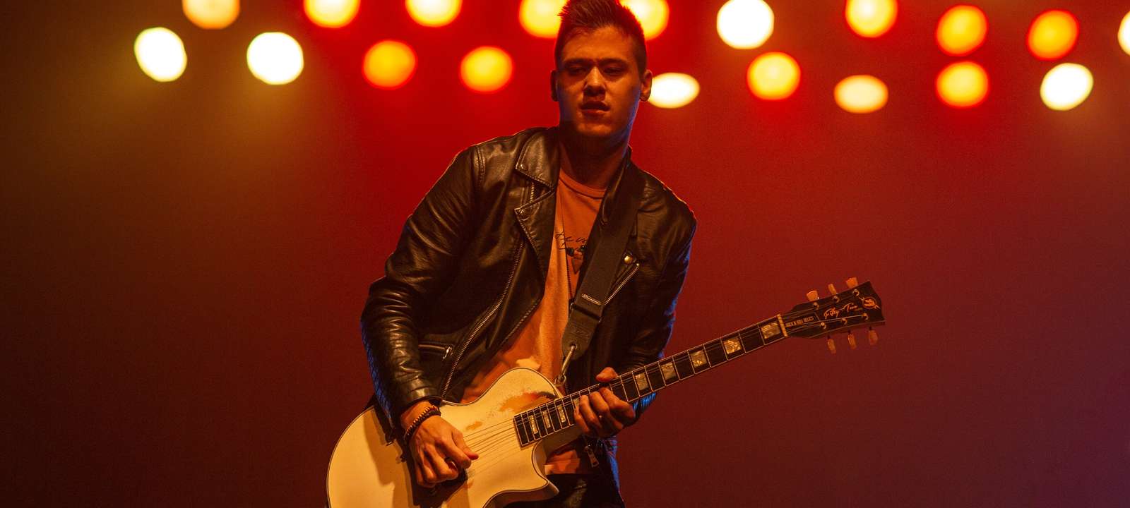 A guitarist playing the guitar on stage.
