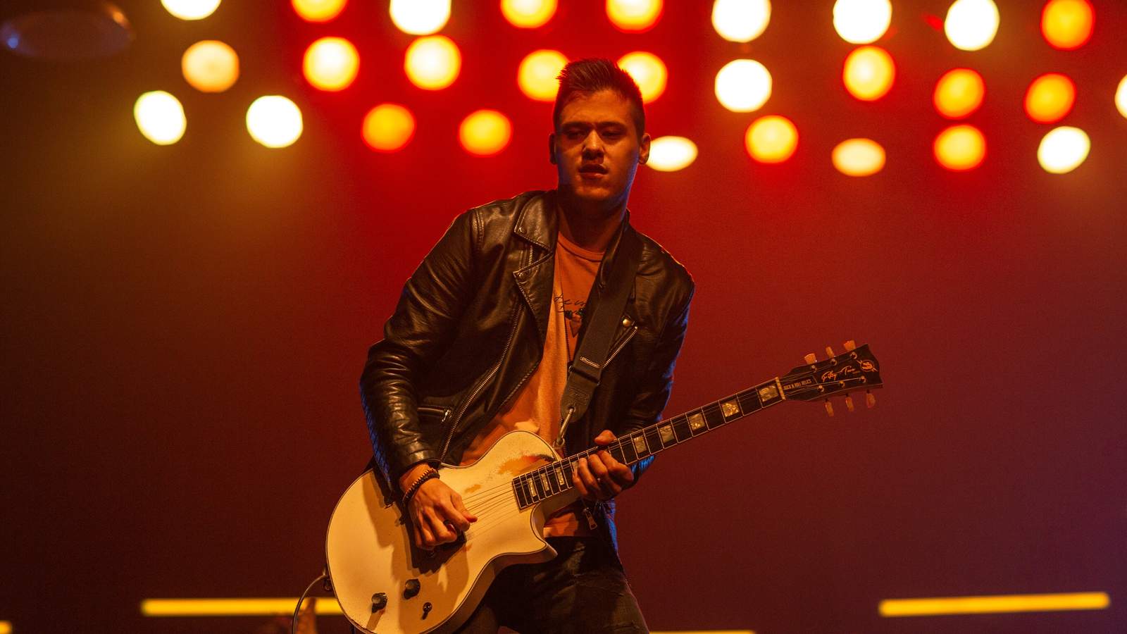 A guitarist playing the guitar on stage.