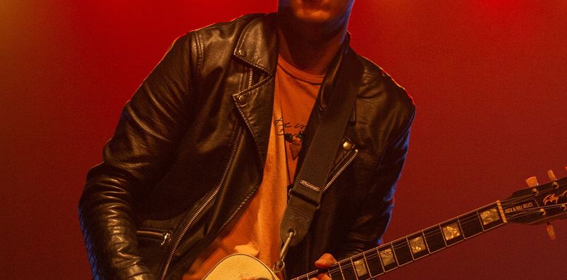 A guitarist playing the guitar on stage.