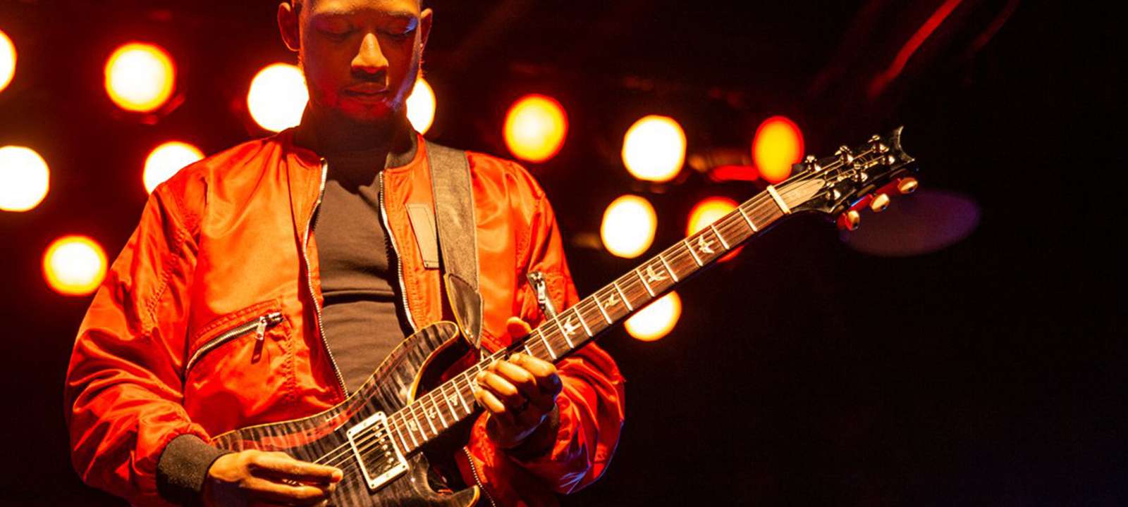 A guitarist playing the guitar on stage.