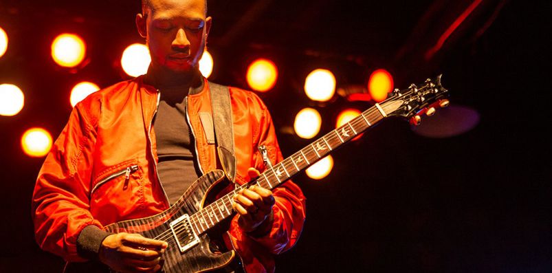 A guitarist playing the guitar on stage.