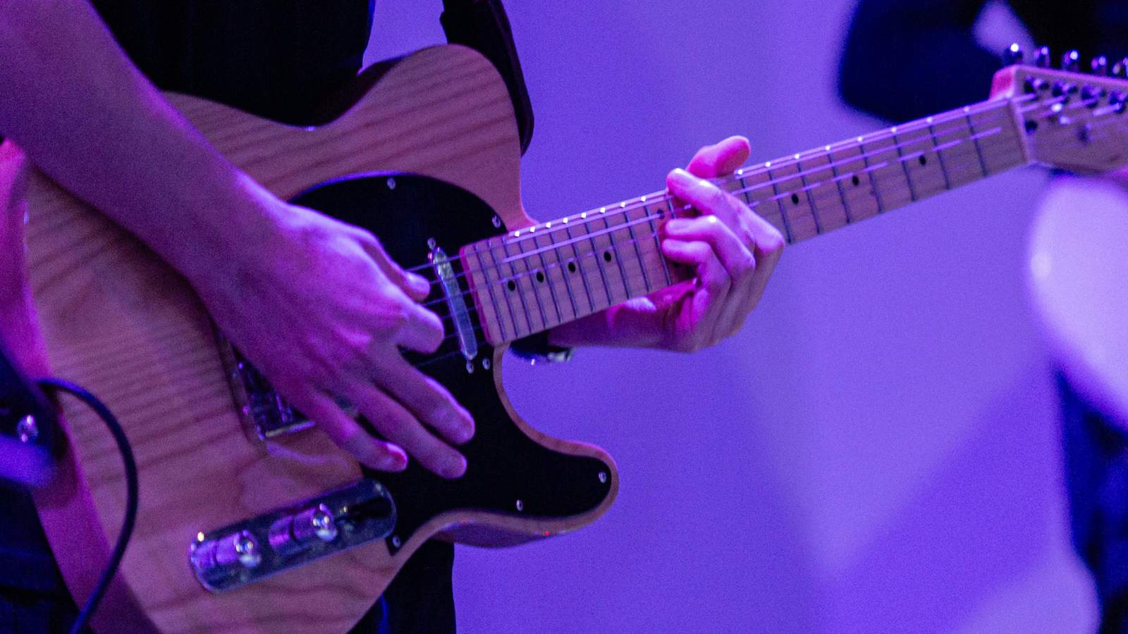 A guitarist playing the guitar on stage.