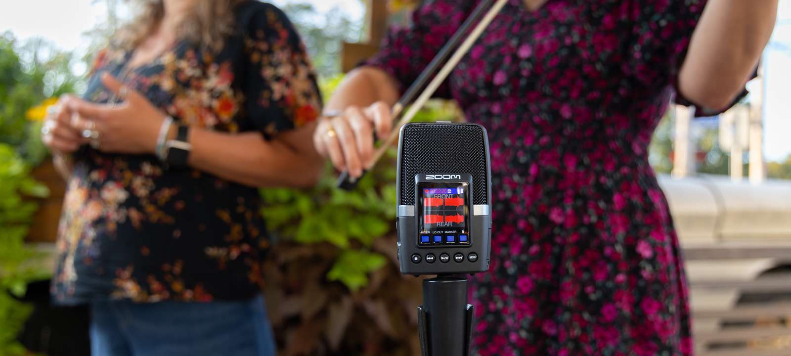 Several musicians standing around an H2essential mounted on a microphone stand, recording their performances