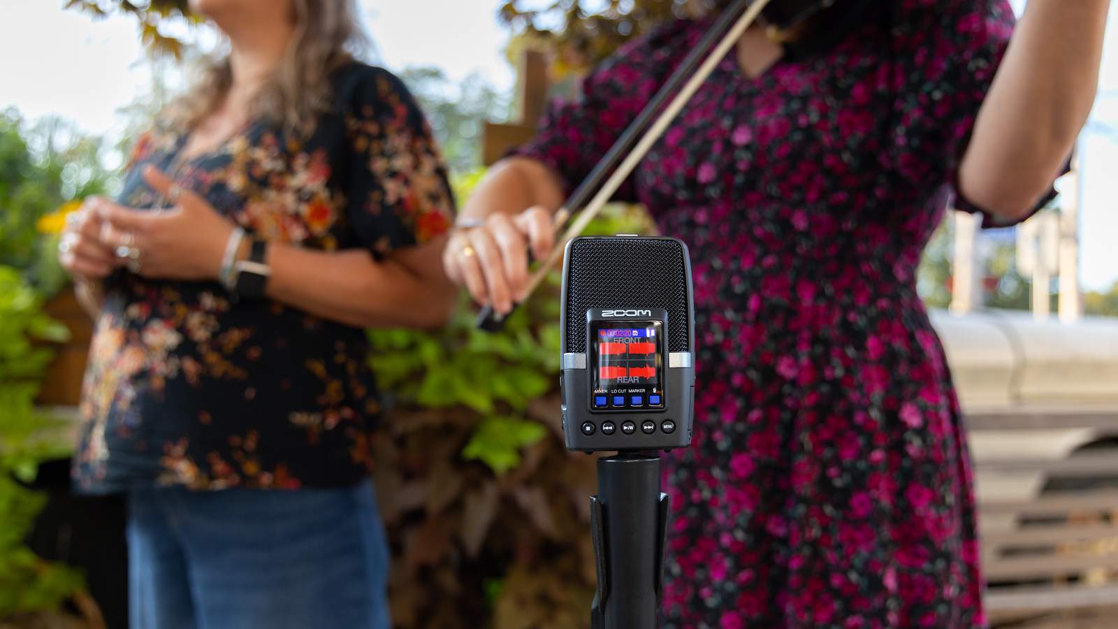Several musicians standing around an H2essential mounted on a microphone stand, recording their performances