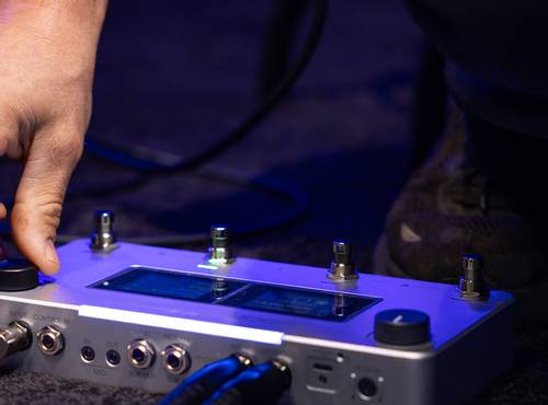ステージ上でNEURIG上のつまみを回して、音色を設定するギタリスト