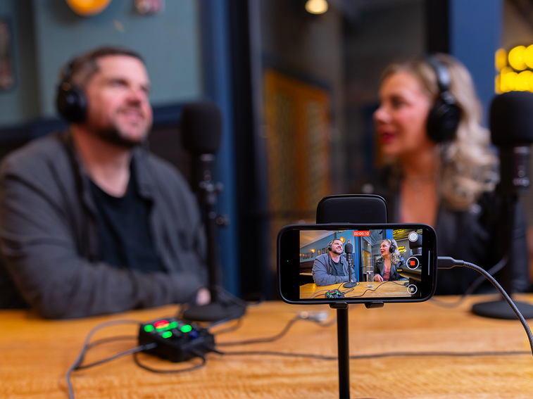 Two podcasters using a smartphone and the PodTrak P2