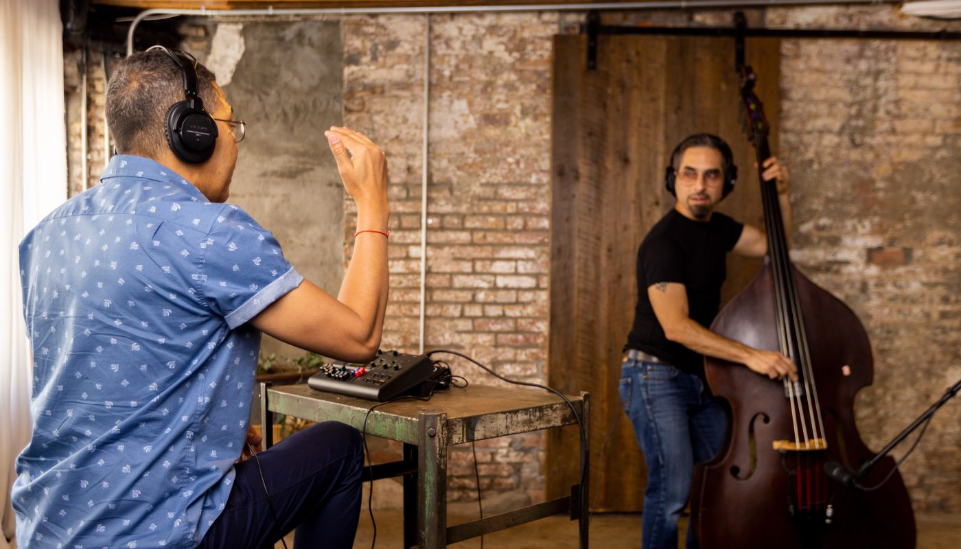 Engineer and bassist recording a bass track with headphones for playback/play along
