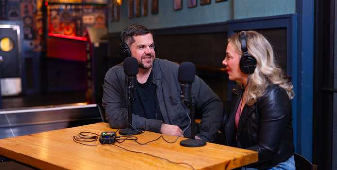 A male-female podcasting duo recording a talk show at a cafe using the PodTrak P2