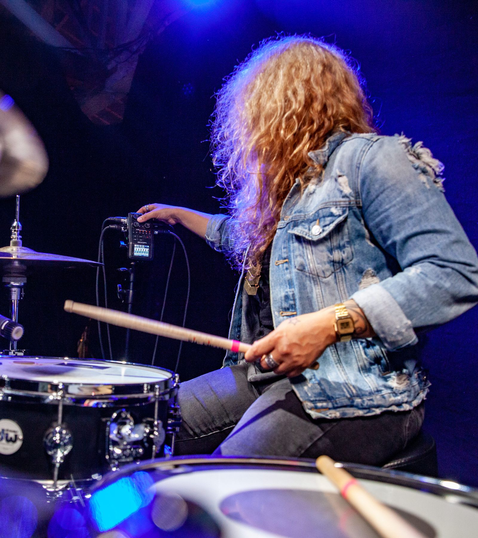 Drummer in the studio adjusting the gain knob on an H6, from behind the drum kit