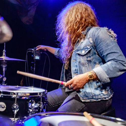 Drummer in the studio adjusting the gain knob on an H6, from behind the drum kit