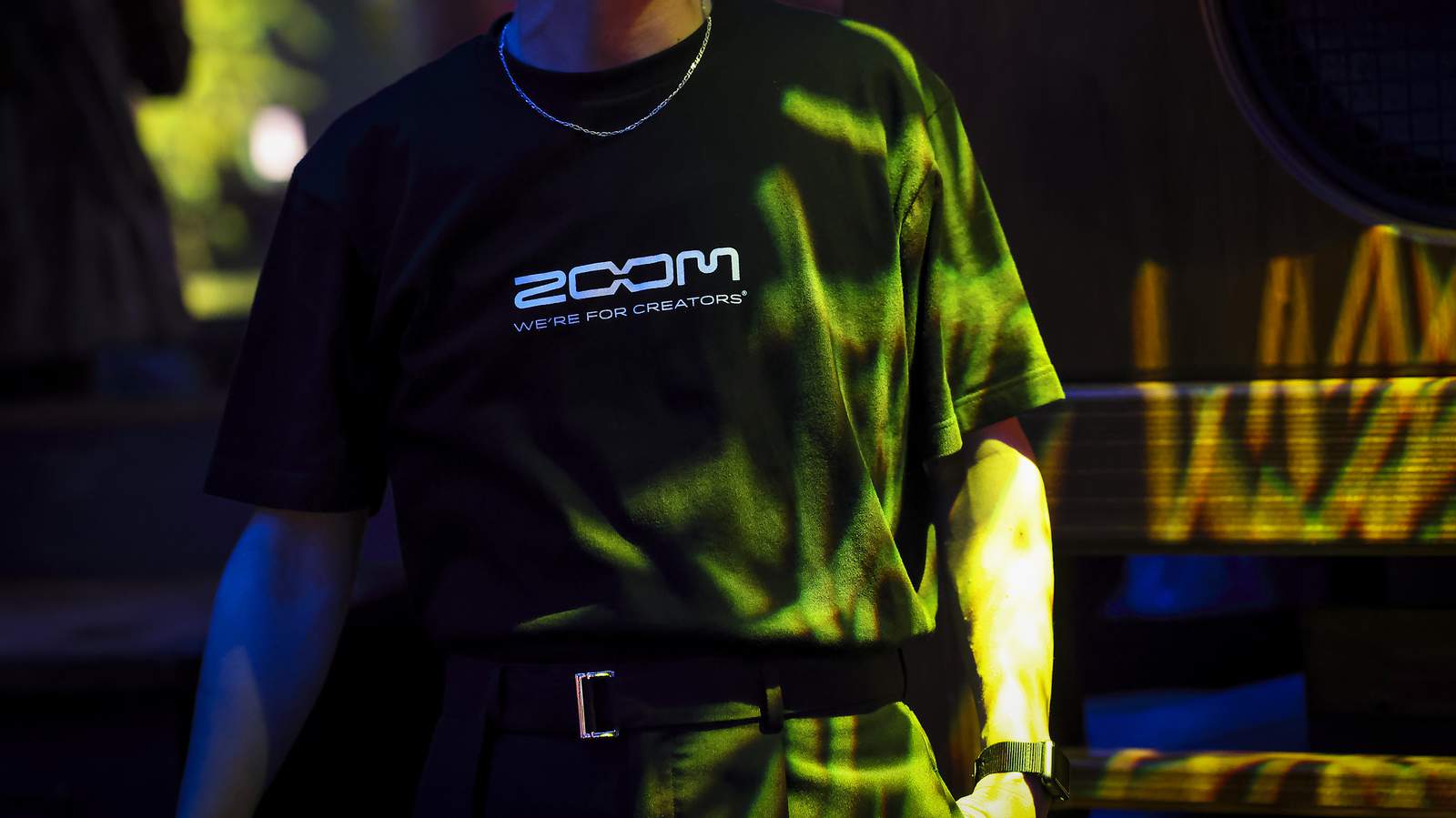 クラブの片隅でたたずむ、ZOOMロゴTシャツを着た男性