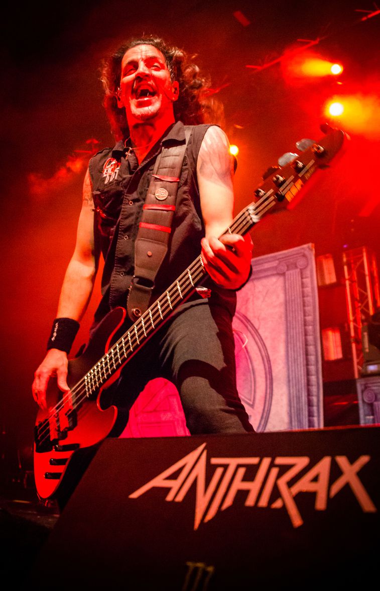 Vertical shot of Frank Bello playing bass live on stage with Anthrax