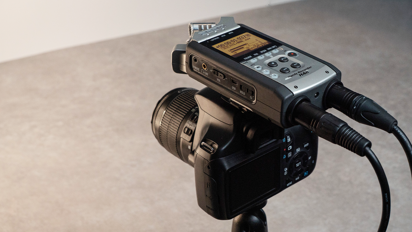 A ZOOM H4n mounted on top of a DSLR camera, recording audio for video.