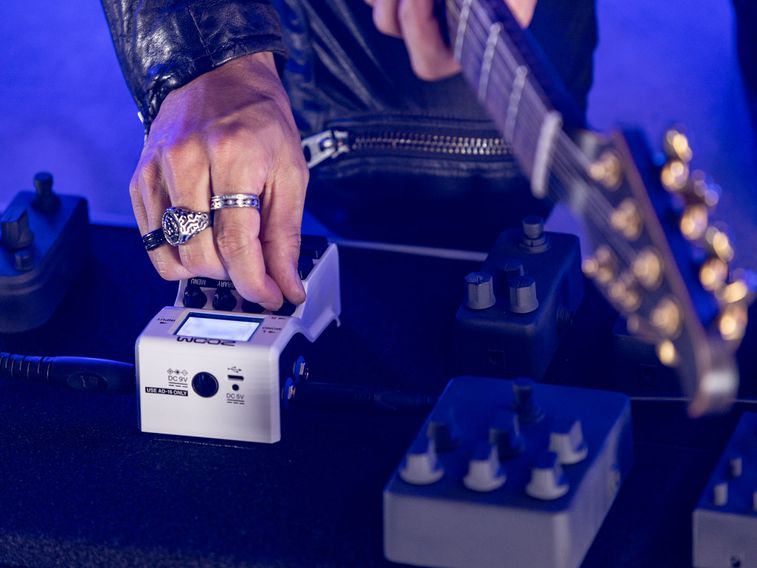 Guitarist adjusting effect parameters using the encoder knobs